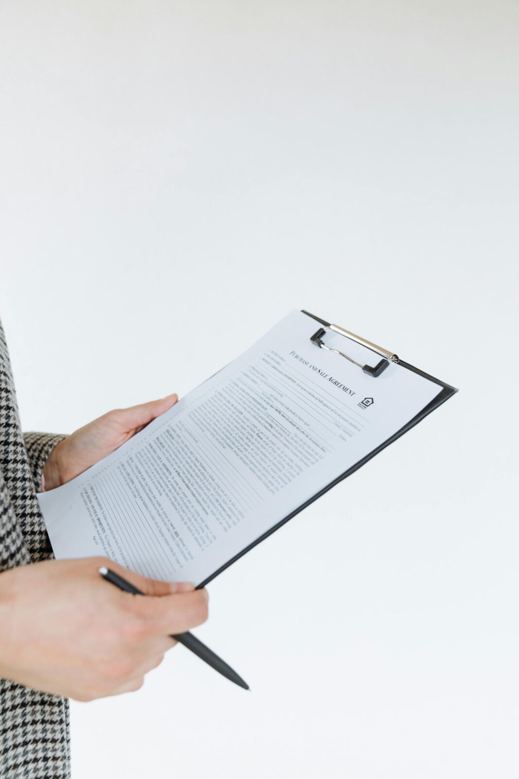 Person holding a filled contract on a clipboard with a pen against a white background.